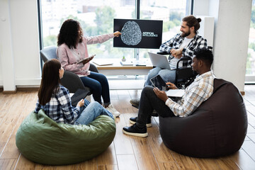 Group of young adults brainstorming artificial intelligence innovations, featuring diverse individuals collaborating on project using modern technology in relaxed workspace.