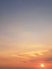 Evening sunset with an orange blue sky – White and grey clouds illuminated by the last remaining rays of the bright orange evening sun, amidst a darkening blue sky.