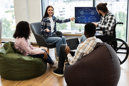 Diverse group of adult engineers of different genders and backgrounds discussing car blueprint design. Teamwork, inclusive environment, and creativity showcased at modern workplace