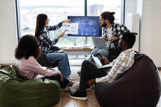 Multiracial team of professionals discussing concepts and designs for a car development project. Includes women and men in adult age range sharing ideas, analyzing graphics