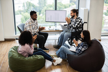 Colleagues of different backgrounds and abilities collaborating and applauding in workspace. Team includes professionals of mixed genders and races, working in comfortable and inclusive environment.