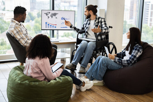 Diverse group of young adults discussing global financial report on monitor in modern office - Powered by Adobe