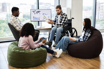 Diverse group including male wheelchair user, analyzing financial charts and global map reports