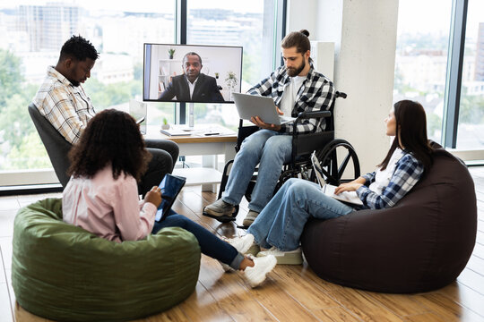 Group of young diverse professionals including men and women meeting, using technology, engaging in video conferencing showing dedication, inclusion, modern workplace values