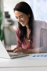 Closeup smiling woman engaged in work on laptop in office