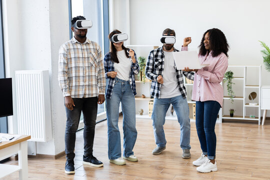 Group of diverse individuals in casual work office setting using virtual reality glasses for entertainment and collaboration, demonstrating innovation, teamwork, and computer technology creativity.
