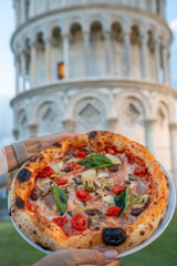 Delicious Italian pizza in front of the iconic Leaning Tower of Pisa at sunset