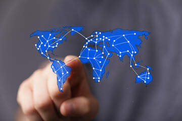 A human hand interacting with a glowing digital world map overlayed with a network of connections,...