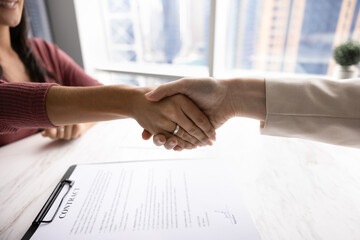 Satisfied female client shaking hands bank advisor after signing contract