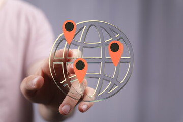 Hand interacting with a digital globe showing multiple location markers. Represents global reach,...