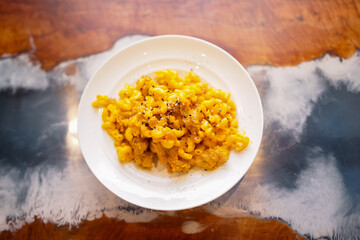 Macaroni and cheese with crispy topping served on white plate, comfort food concept in close-up.