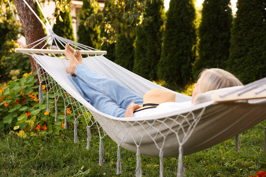 Senior woman resting in comfortable hammock outdoors - Powered by Adobe