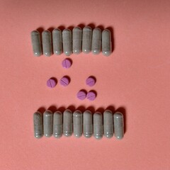 seis píldoras de color rojo con raya en centro y diecisiete cápsulas transparentes con polvo color marrón. farmacia, química, medicina © Elena G. Madrid