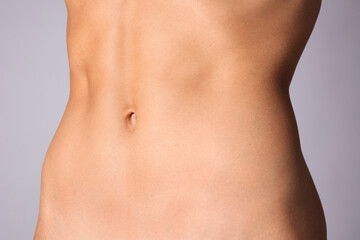Woman with flat belly on grey background, closeup