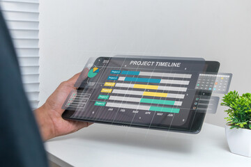 A man works on tablet computer to check project schedules, milestones, and planning progress to match the predetermined schedule