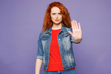 Young sad serious strict ginger woman she wears red t-shirt denim shirt showing stop gesture with palm look camera isolated on plain pastel light purple background studio portrait. Lifestyle concept.