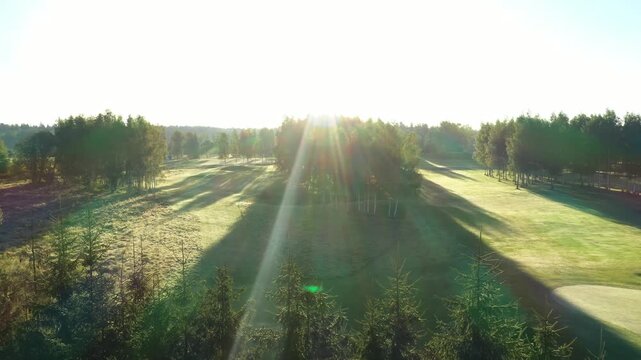 Valmiera, Latvia - August 27, 2025 - Golden sunrise over Avoti Golf Course with long shadows stretching across manicured greens and trees, creating a peaceful and scenic morning landscape.
