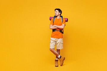 Young traveler man carry backpack with stuff mat look aside on area isolated on plain yellow background. Tourist leads active healthy lifestyle walk on spare time Hiking trek rest travel trip concept