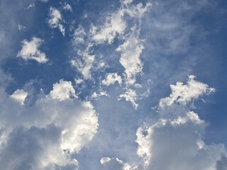 Late afternoon sun illuminating the clouds in the blue sky – White and grey clouds illuminated by the strong rays of the late afternoon sun, amidst a blue sky.