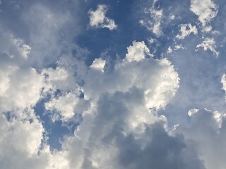 Late afternoon sun illuminating the clouds in the blue sky – White and grey clouds illuminated by the strong rays of the late afternoon sun, amidst a blue sky.