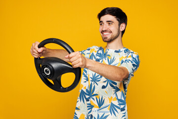 Side profile view young man he wear blue beach t-shirt casual clothes hold steering wheel driving car look aside on area isolated on plain yellow orange background studio portrait. Lifestyle concept.