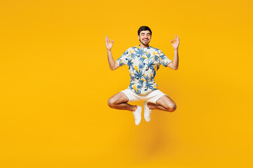 Obraz premium Full body young man wear blue t-shirt casual clothes jump high hold spreading hands in yoga om aum gesture relax meditate try to calm down isolated on plain yellow orange background Lifestyle concept