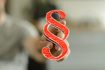 A hand presents a red paragraph symbol, symbolizing law, justice, and legal matters. Perfect for...