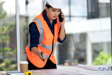 Asian adult professional woman engineer discusses building plans phone manages project reviews...