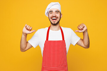 Young smiling housewife housekeeper chef cook baker man he wear red apron toque hat pointing thumb...