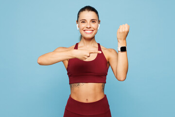 Young fitness trainer instructor sporty woman sportsman in red sportswear headphones training in home gym use blank screen smart watch isolated on plain blue background Workout sport fit abs concept