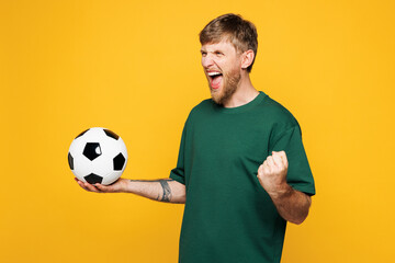 Young happy man fan wearing basic green t-shirt cheer up support football sport team hold in hand...
