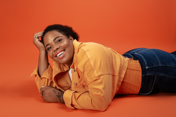 Stylish plus size woman embraces autumn fashion in vibrant studio setting