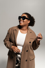 Obraz premium Stylish plus size woman in trendy autumn outfit poses confidently in studio light