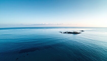 Sunlit Blue Ocean with Distant Shoreline and Small Dark Structures in a Panoramic View