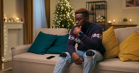 Sitting on a sofa, a young student of multi-racial background receives news that his flight home...