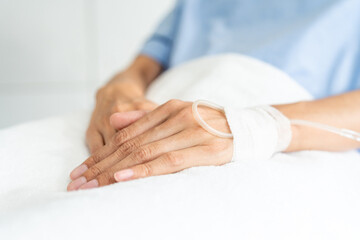 Asian female cancer patient resting in hospital bed with IV line. Undergoing chemo treatment...