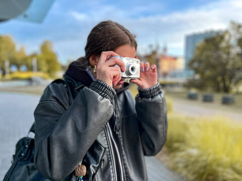 een girl exploring vintage photography with retro point-and-shoot camera outdoors. Embracing analogue lifestyle, slow living, and nostalgic digital minimalism.