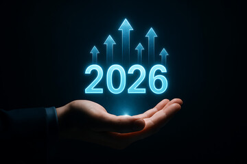 An open hand holding the glowing blue numbers 2026 with multiple rising arrows indicating business progress, success, and a positive growth trajectory for the new year