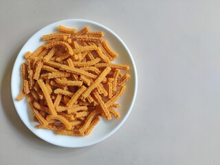 Close-up of homemade Murukku sticks in a white ceramic plate/White background/Still life/Copy space