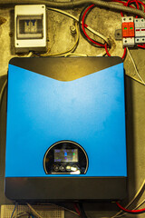 A complete solar power system: detailed blue panels and a modern, bright blue inverter with a digital display, illustrating the technology for clean, sustainable energy generation.

