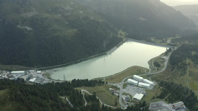 Drone push-in across the Speichersee reservoir dam surrounded by alpine peaks. Great for nature, tourism, and sustainable infrastructure footage.