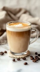 A transparent cup with coffee and milk, with coffee beans on a brown background