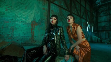 Sequence showing two Asian models shifting poses wearing PVC trench coat in loft shoot, teal-lit - Powered by Adobe
