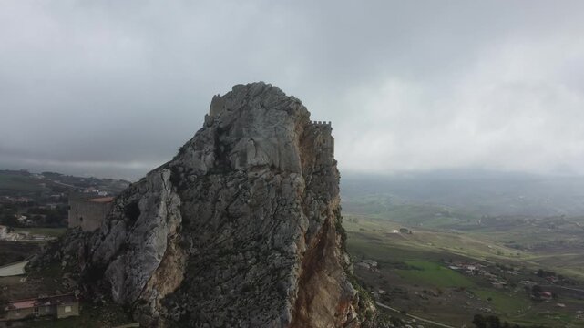 Aerial 4k drone footage of Mussomeli Castle in Sicily, Italy, featuring the historic fortress, dramatic misty atmosphere, surrounding hills, and panoramic views of the landscape
