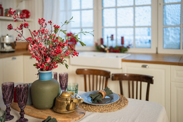 Classical Christmas decorated interior kitchen. Modern classic style interior design apartment dining with red frosty branches bouquet ornament Christmas decorations. Christmas eve at home