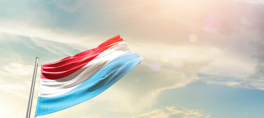 Luxembourg  flag waving proudly under a bright sky with text happy independence day. Luxembourg...