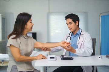 Doctor examining mature woman's arm in medical office