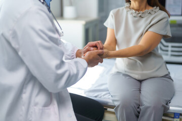 Fototapeta premium Doctor comforting patient by holding her hands in hospital room