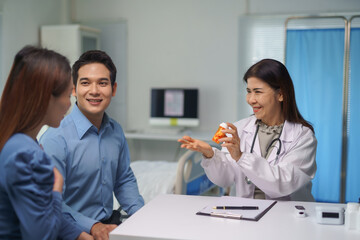 Doctor prescribing medicine to young couple in hospital room