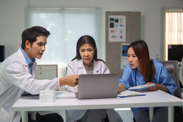 Obraz premium Doctors and nurse working together on a laptop in hospital meeting room